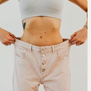 Weight loss progress shown by woman wearing oversized pants after GLP-1 medication like Mounjaro or Ozempic.