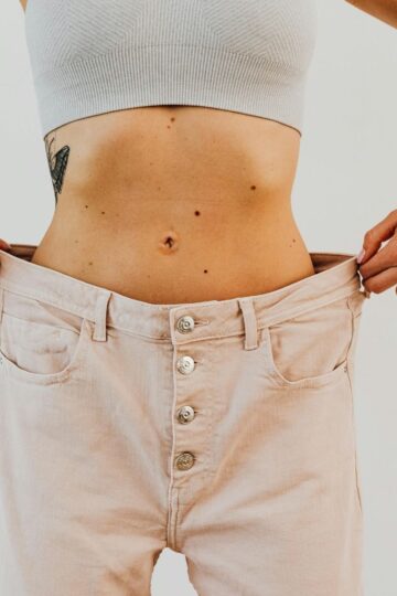 Weight loss progress shown by woman wearing oversized pants after GLP-1 medication like Mounjaro or Ozempic.