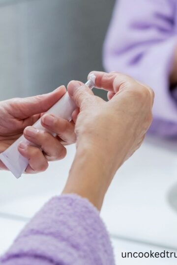 hands of a woman using a tube of cream.