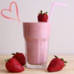 Image of a protein shake in a glass decorated with strawberries.