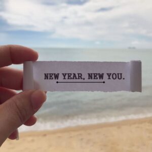image of person on the beach showing a piece of paper with writing on it.