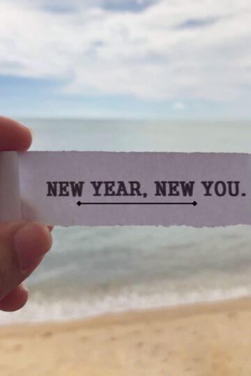 image of person on the beach showing a piece of paper with writing on it.
