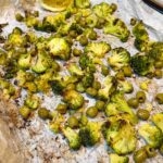 Roasted broccoli and olives on a baking sheet.